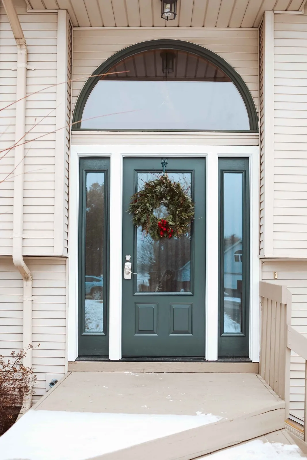 Green entry door under an arched transom